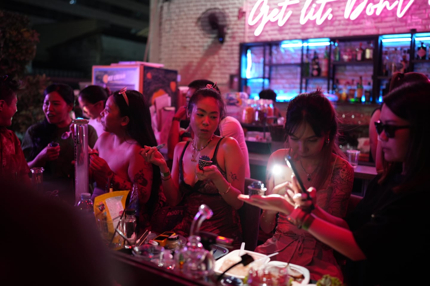 Guests gathered around a table under pink lighting at a FOURTWENTY event.